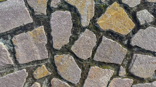 Nüanslı toprak tonları olan engebeli bir taş duvarın karmaşık detayları.