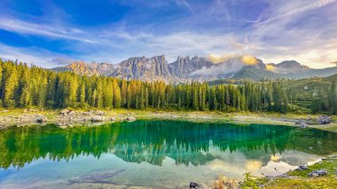 Lago di Carezza, 1519 metrede, zümrüt suları olan bir dağlık hazine, ladin ağaçları tarafından beşikte, görkemli Dolomitlere karşı, doğanın canlı renklerinde boyanmış bir peri masalı.