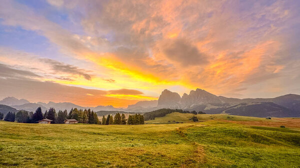 Alpe di Siusi, крупнейшее альпийское пастбище в Европе в Южном Тироле, Италия. Красота Доломитов на восходе солнца, холст из лугов, гор и сенных хижин, море катящихся зеленых волн