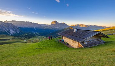 SECEDA, İtalya. 19 Eylül 2023 'te. Kulübede fotoğrafçı, Seceda 'nın gündoğumunu çekiyor. İkonik tepeler ve çayırlar parıldıyor, Dolomitlerin kalbinde pitoresk bir sabah sahnesi çiziyor.