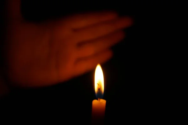 Human hands protect candlelight at night that illuminates things.