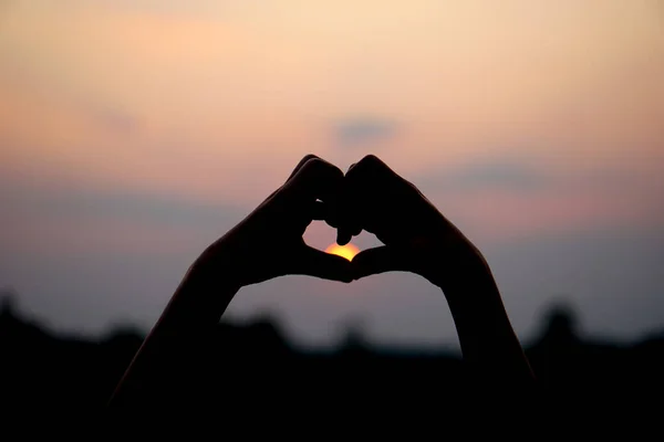 heart shaped human hand silhouette sunset background