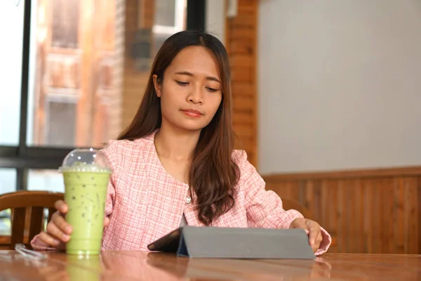 Asian woman braces watch computer Drink green tea to refresh.