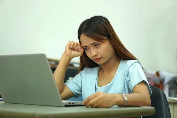 Asian woman looking at computer Frustrated by declining earnings