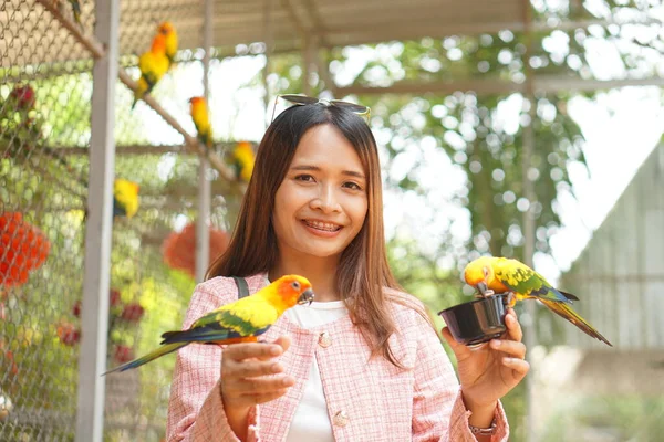 庭でアジアの女性の餌オウム — ストック写真
