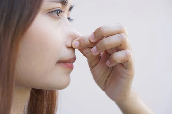 Asian woman covering her nose with her hands due to a bad smell