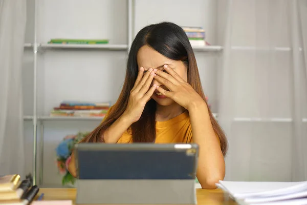 Asian woman at home Having eye pain from watching a computer for a long time