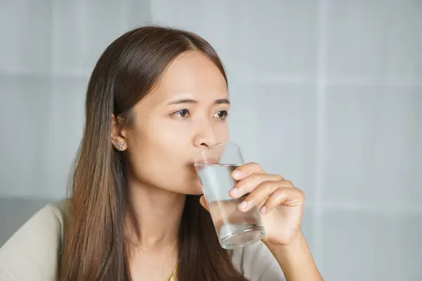 Asian woman drinking water, working at home