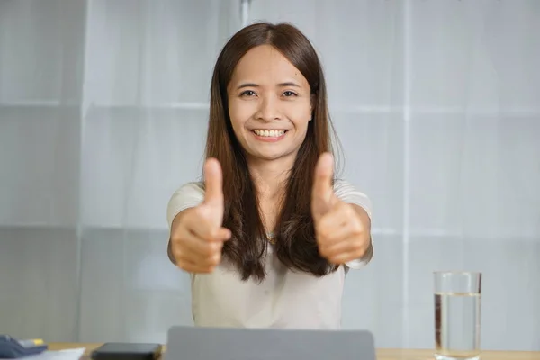 Asian woman working at home Raise your hand as excellent