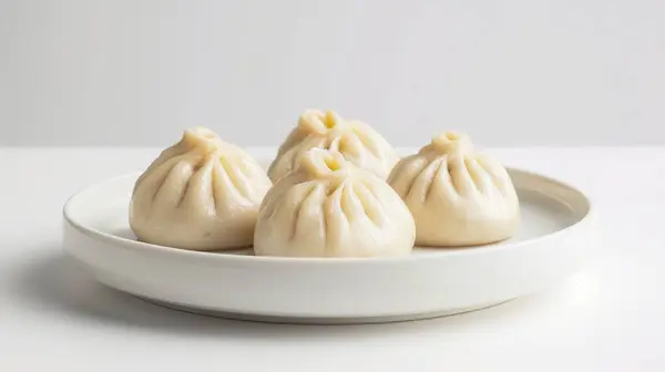 stock image Three mini steamed pork bao on a white plate and white background