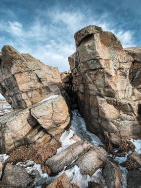 Okotoks 'taki Büyük Kaya' nın dengesiz görüntüsü dramatik bölünmesini gözler önüne seriyor Alberta. Kar ve dağınık taşlar boşluğu dolduruyor, parlak bir kış gökyüzü kayanın engebeli dokusunu aydınlatıyor..