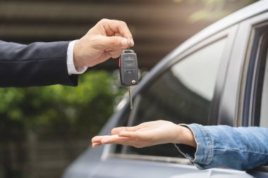 transportation rental automotive business concept. Close up hands of rental auto agent giving car remote key to client to travel sightseeing.