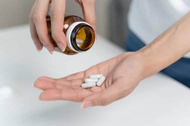 close up person pouring multivitamin capsules to her hands