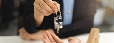 Realtor agent giving a key of apartment to new owner after signed lease agreement.