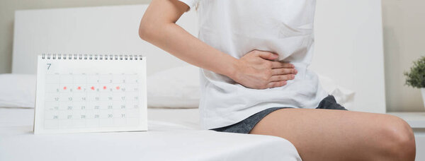 Месячные симптомы менструации срок концепции. Закрыть календарь маркировки менструации день и женщина имеют боль в животе в качестве фона.