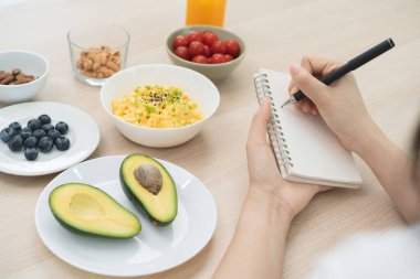young female planning menu to eat ketogenic diet during weight loss program.