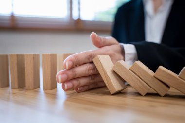 Protection finance from domino effect concept. Hands stop domino effect before destroy stack of money.