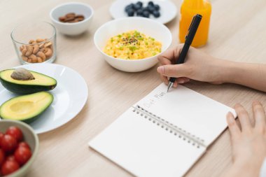 young female planning menu to eat ketogenic diet during weight loss program.