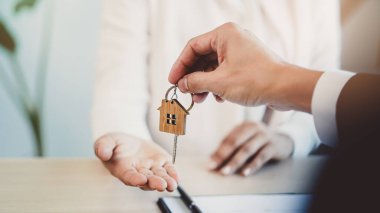 close up view hand of property realtor / landlord giving key house to buyer / tenant.