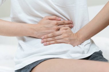 person feeling stomach pain menstruation on the bed.