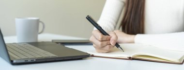 closeup hand of woman writing ideas to notebook