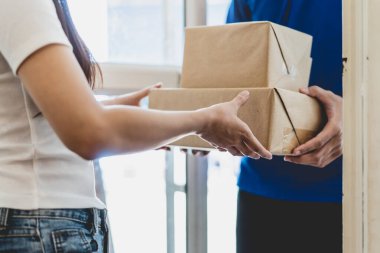 Close up hands the client receiving package box from the delivery man at home