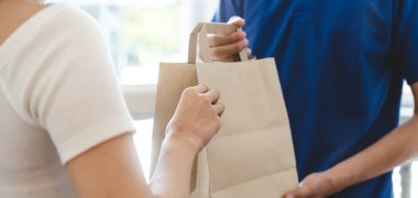 client in protective face mask receiving package from delivery m