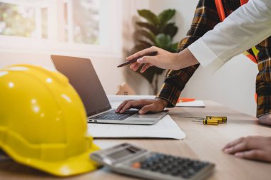 Contractor and client discussing plan of renovating the house and pointing to the laptop computer screen.