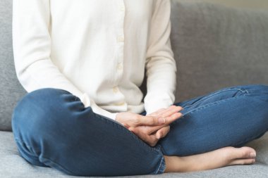 Wellbeing peaceful mind lifestyles,  Close up hand of young Asian women focus on breath harmony to refresh mindfulness on sofa in the living room at home.