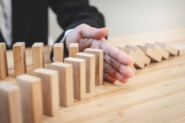 Protection finance from domino effect concept. Hands stop domino effect before destroy stack of money.