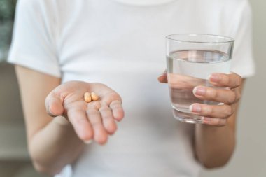 close up person pouring multivitamin capsules to her hands
