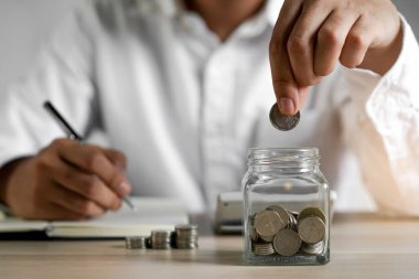 Close up hands of man putting coins into piggy bank