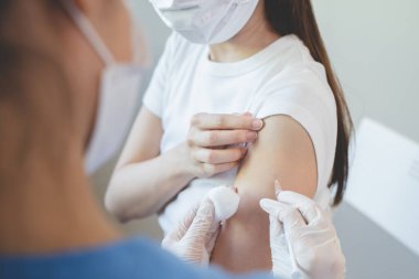 People getting a vaccination to prevent pandemic concept. Woman in medical face mask  receiving a dose of immunization coronavirus vaccine from a nurse at the medical center hospital