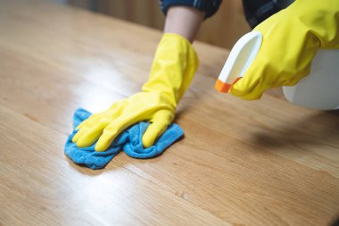 Asian woman cleaning the table surface with towel and spray detergent
