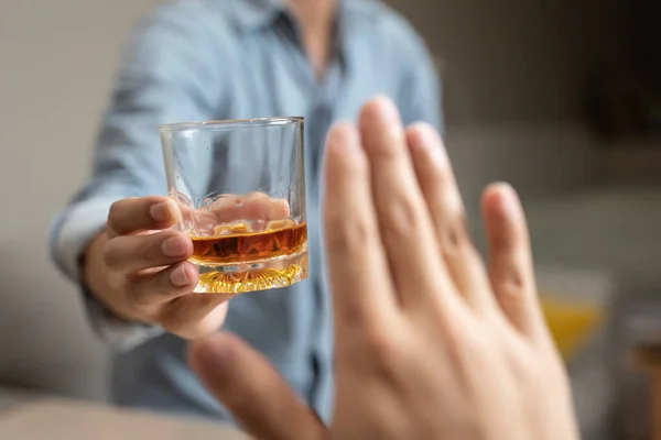 person deny alcohol drink from his friend