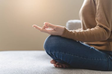 Wellbeing peaceful mind lifestyles,  Close up hand of young Asian women focus on breath harmony to refresh mindfulness on sofa in the living room at home.