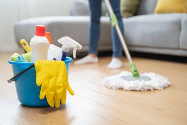 happy Female housekeeper service worker mopping living room floor by mop and cleaner product to clean dust.