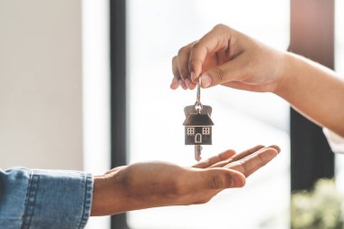Realtor agent giving a key of apartment to new owner after signed lease agreement.
