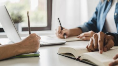 Close up hands of university student studying in class and taking note in notebook.