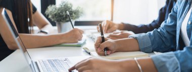 Close up hands of university student studying in class and taking note in notebook.