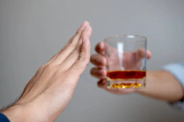 Drunk men deny drinking more glass of whisky by pushing away.