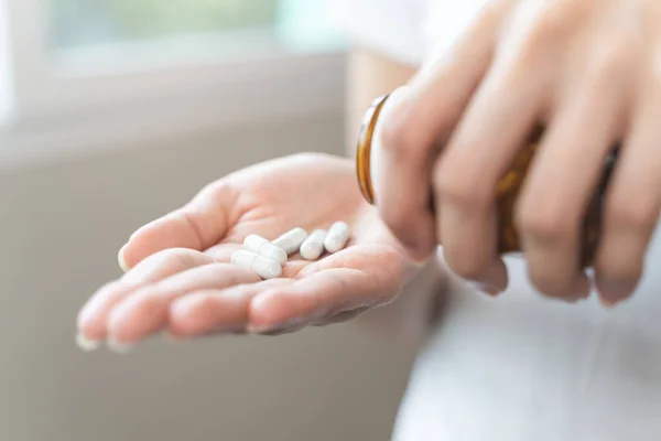close up person pouring multivitamin capsules to her hands