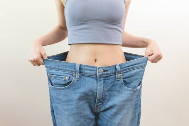 person wearing oversized old jean pants before weight loss success isolated on background.