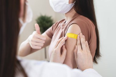 person confident after getting vaccine by  showing sign thumb up.