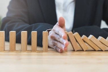 Protection finance from domino effect concept. Hands stop domino effect before destroy stack of money.