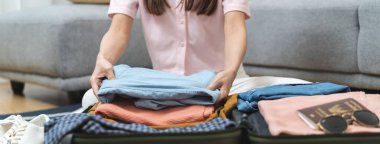 Prepare to travel concept. Close-up hands of female organizing clothes in suitcase prepare to leave hotel