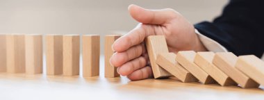 Protection finance from domino effect concept. Hands stop domino effect before destroy stack of money.