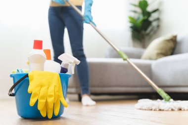 happy Female housekeeper service worker mopping living room floor by mop and cleaner product to clean dust.