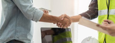 construction worker and contractor. Client shaking hands with team builder in renovation site.