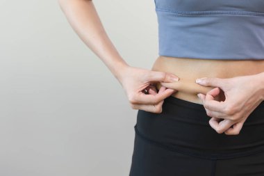 Close up Woman squeeze her belly and measuring fat on her waist
